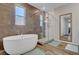 Elegant bathroom featuring a soaking tub, glass-enclosed shower, and stylish wood-look tile flooring at 10161 Bismarck Palms Ave, Las Vegas, NV 89166