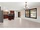 Open-concept living area with kitchen island, tile floors, and modern chandelier at 11755 Garland Grove Ln, Las Vegas, NV 89183