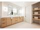 Elegant bathroom featuring dual sinks, a large mirror, modern lighting, and built-in storage shelves at 1811 Country Meadows Dr, Henderson, NV 89012