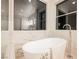 Modern bathroom featuring a soaking tub with sleek fixtures and marble surround, with a view from a window at 1811 Country Meadows Dr, Henderson, NV 89012