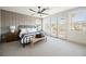 A well-lit main bedroom with a ceiling fan, neutral carpet, and a balcony with views of mountains at 1811 Country Meadows Dr, Henderson, NV 89012