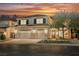 Inviting two-story home with a three-car garage, lush landscaping, and warm exterior lighting at sunset at 1811 Country Meadows Dr, Henderson, NV 89012