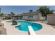 Inviting in-ground pool with diving board and rock feature complemented by a covered patio, perfect for outdoor relaxation at 1852 E Viking Rd, Las Vegas, NV 89169