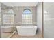 Elegant bathroom with a soaking tub, glass shower, and unique window design at 1999 Oliver Springs St, Henderson, NV 89052