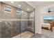 Bathroom features a frameless shower, grey tile, and a door leading to a bedroom at 2069 Alto Vista Dr, Henderson, NV 89052