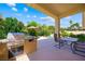 Outdoor patio with built-in grill, dining table, and lush landscaping near the pool area at 2113 Scarlet Rose Dr, Las Vegas, NV 89134