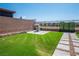 Backyard featuring a manicured lawn, patio with grill, and an iron fence at 2577 Tolmezzo St, Henderson, NV 89044
