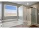 Bathroom showcasing a soaking tub with a tile surround and a glass-enclosed shower at 2577 Tolmezzo St, Henderson, NV 89044