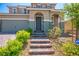 Front exterior of a two-story home featuring brick steps leading to a covered porch and green landscaping at 2577 Tolmezzo St, Henderson, NV 89044