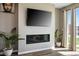 Living room with a fireplace, television, gray walls, wood floors, sliding doors and plants at 2577 Tolmezzo St, Henderson, NV 89044