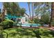 Lush backyard featuring a sparkling blue pool, green lawn, mature trees, and a shaded outdoor area at 3320 Indian Moon Dr, Las Vegas, NV 89129