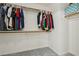 Spacious walk-in closet with ample hanging space on wooden rods and neutral gray carpeting at 3320 Indian Moon Dr, Las Vegas, NV 89129