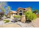 Exterior view of a home with desert landscaping, rocks, mature shrubs, and a warm color palette at 4620 N Tee Pee Ln, Las Vegas, NV 89129