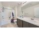 Well-lit bathroom featuring double sinks, large mirror, shower over tub, and neutral tiling at 5660 Oasis Ridge St, North Las Vegas, NV 89031