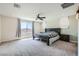 Spacious bedroom with a large window, ceiling fan, and neutral carpet at 5660 Oasis Ridge St, North Las Vegas, NV 89031
