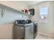 Bright laundry room featuring stainless steel washer and dryer with storage shelf at 5660 Oasis Ridge St, North Las Vegas, NV 89031