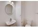 Neat half bath with a pedestal sink, round mirror and low-flow toilet at 6264 Canebrake Ct, Las Vegas, NV 89141