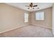 Neutral bedroom featuring a ceiling fan, two windows with blinds, and neutral carpeting at 6264 Canebrake Ct, Las Vegas, NV 89141