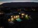 Aerial view of a modern home with a pool, outdoor lounge, and expansive landscaping at night at 68 Sun Glow Ln, Las Vegas, NV 89135