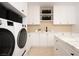 Modern laundry room with front load washer and dryer, ample storage, and marble countertops at 68 Sun Glow Ln, Las Vegas, NV 89135