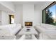 Elegant living room featuring a modern fireplace, white sofas, marble coffee table, and a view of the outdoors at 68 Sun Glow Ln, Las Vegas, NV 89135