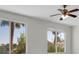 Bedroom with a ceiling fan and large windows looking out onto a palm tree at 6909 Fruit Flower Ave, Las Vegas, NV 89130