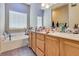 Well-lit bathroom featuring a bath tub, window, and a vanity with sink at 6916 Gothic Marigold St, Las Vegas, NV 89149