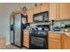 Compact kitchen featuring black appliances and wooden cabinets for ample storage at 6916 Gothic Marigold St, Las Vegas, NV 89149