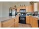 Functional kitchen with wooden cabinets, black appliances, and tile flooring at 6916 Gothic Marigold St, Las Vegas, NV 89149