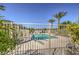 Community pool with clear blue water, palm trees, and a secure fence, offering a relaxing and private oasis at 7472 Garnet Moon St, North Las Vegas, NV 89084