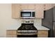 Efficient kitchen featuring stainless steel microwave, stove, and light-colored cabinets at 7885 W Flamingo Rd # 1131, Las Vegas, NV 89147