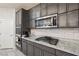 This kitchen features sleek gray cabinets, granite countertops, stainless appliances, and modern backsplash at 9238 Bluemist Falls St, Las Vegas, NV 89123