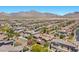 Expansive aerial view showcases a residential area with terracotta rooftops and desert landscaping, set against a backdrop of mountains at 12269 Catanzaro Ave, Las Vegas, NV 89138