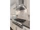 Close-up view of stainless steel range hood and gas cooktop with tile backsplash at 12269 Catanzaro Ave, Las Vegas, NV 89138