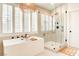 Bright modern bathroom with a soaking tub, shutters, and a glass-encased shower at 1513 Ravanusa Dr, Henderson, NV 89052