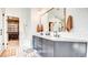 This bathroom has a double vanity with a quartz countertop, stylish fixtures, and a beautifully tiled herringbone wall at 1513 Ravanusa Dr, Henderson, NV 89052