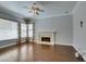 Living room featuring a fireplace, hardwood floors, a ceiling fan, and large windows with wooden blinds and decorative drapes at 1813 Francisco Peak Pl, Las Vegas, NV 89128