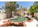 Relaxing backyard pool with a rock border, set against a charming home exterior and mature shade trees at 1813 Francisco Peak Pl, Las Vegas, NV 89128