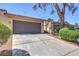 Exterior shot of a well-maintained townhome showing the driveway, mature shrubs, and a two-car garage at 1857 Arbol Verde Way, Las Vegas, NV 89119
