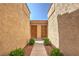 Charming walkway view featuring two wood entry doors, flanked by manicured green bushes and red rock landscaping at 1857 Arbol Verde Way, Las Vegas, NV 89119