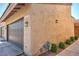 Image shows attached garage, green bushes, neutral stucco, and decorative outdoor lighting at 1857 Arbol Verde Way, Las Vegas, NV 89119