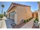 Neutral stucco exterior, attached garage, tiled roof, manicured bushes and walkway leading to the front entrance at 1857 Arbol Verde Way, Las Vegas, NV 89119
