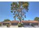 Charming single-story townhome with a tile roof, well-manicured front yard, and a mature tree in the front at 1857 Arbol Verde Way, Las Vegas, NV 89119