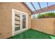 Enclosed patio with artificial turf, stucco walls, and a view of greenery beyond the pergola at 1857 Arbol Verde Way, Las Vegas, NV 89119