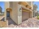 Close up of home's stucco exterior, showing a two-car garage, an arched entry and a paver driveway at 3164 Bormida Ave, Henderson, NV 89044
