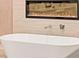 Close-up of a luxurious soaking tub and accent wall with a modern, sleek fireplace at 4 Via Vittorio Pl, Henderson, NV 89011