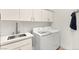 Well-equipped laundry room with white cabinetry, a stainless steel sink and modern washer and dryer at 4 Via Vittorio Pl, Henderson, NV 89011