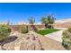 Backyard featuring a small lawn area, low shrubs, rock landscaping, and a concrete patio at 410 Aloha Dr, Henderson, NV 89015