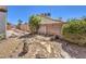 Spacious backyard with rock and gravel landscaping, complemented by green bushes and a stone border at 410 Aloha Dr, Henderson, NV 89015