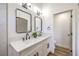 Bathroom vanity featuring a double sink, quartz countertop, black fixtures, and modern decorative lighting at 410 Aloha Dr, Henderson, NV 89015